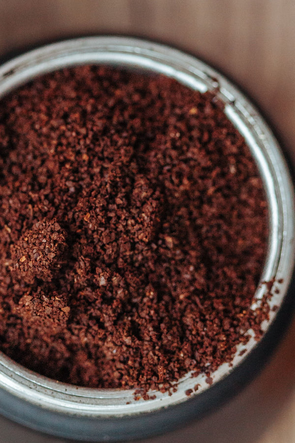 Close-up of medium-coarse ground coffee sitting in a stainless steel grinder bowl after grinding